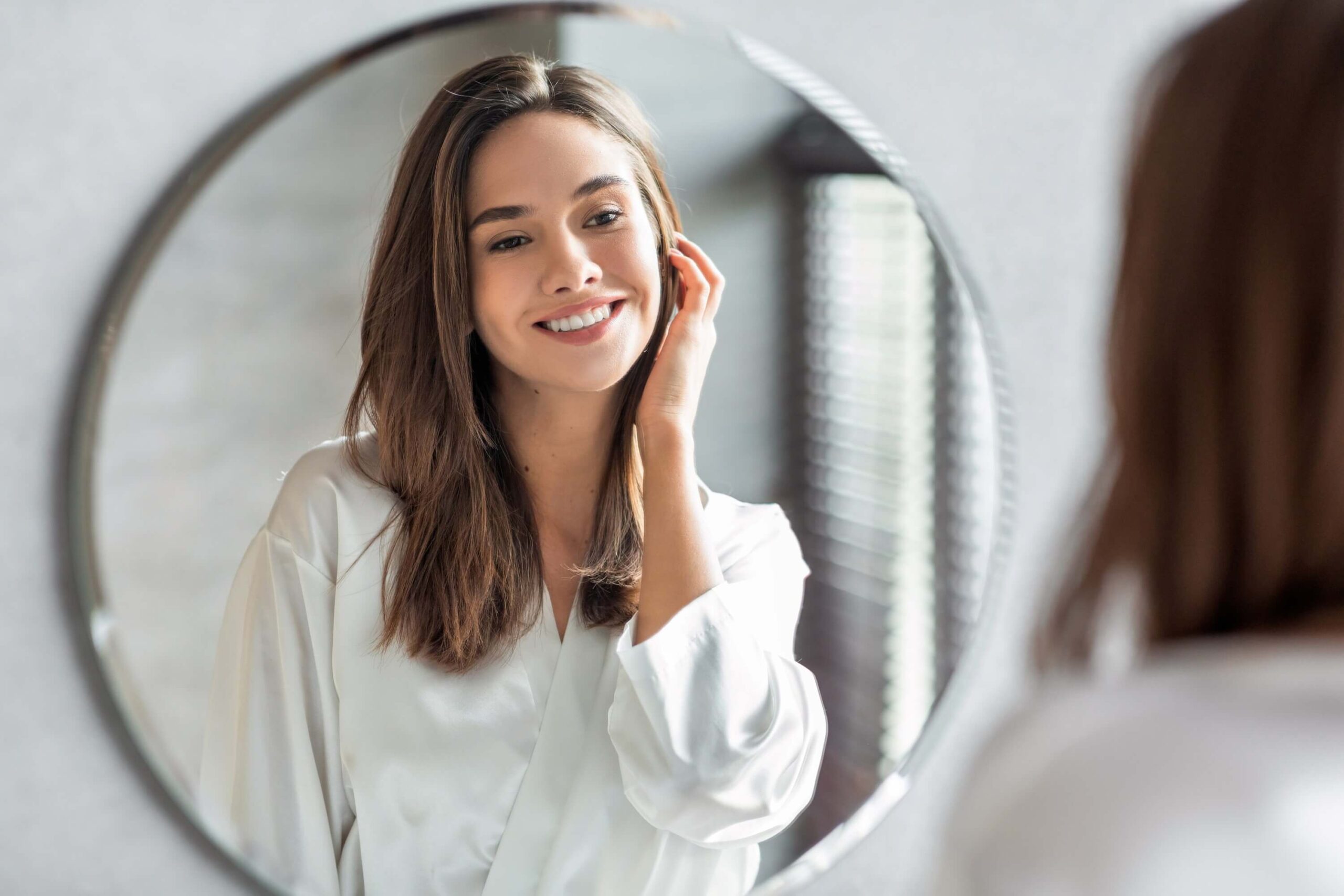 Concepto de belleza. Retrato De Atractiva Mujer Feliz Mirando El Espejo